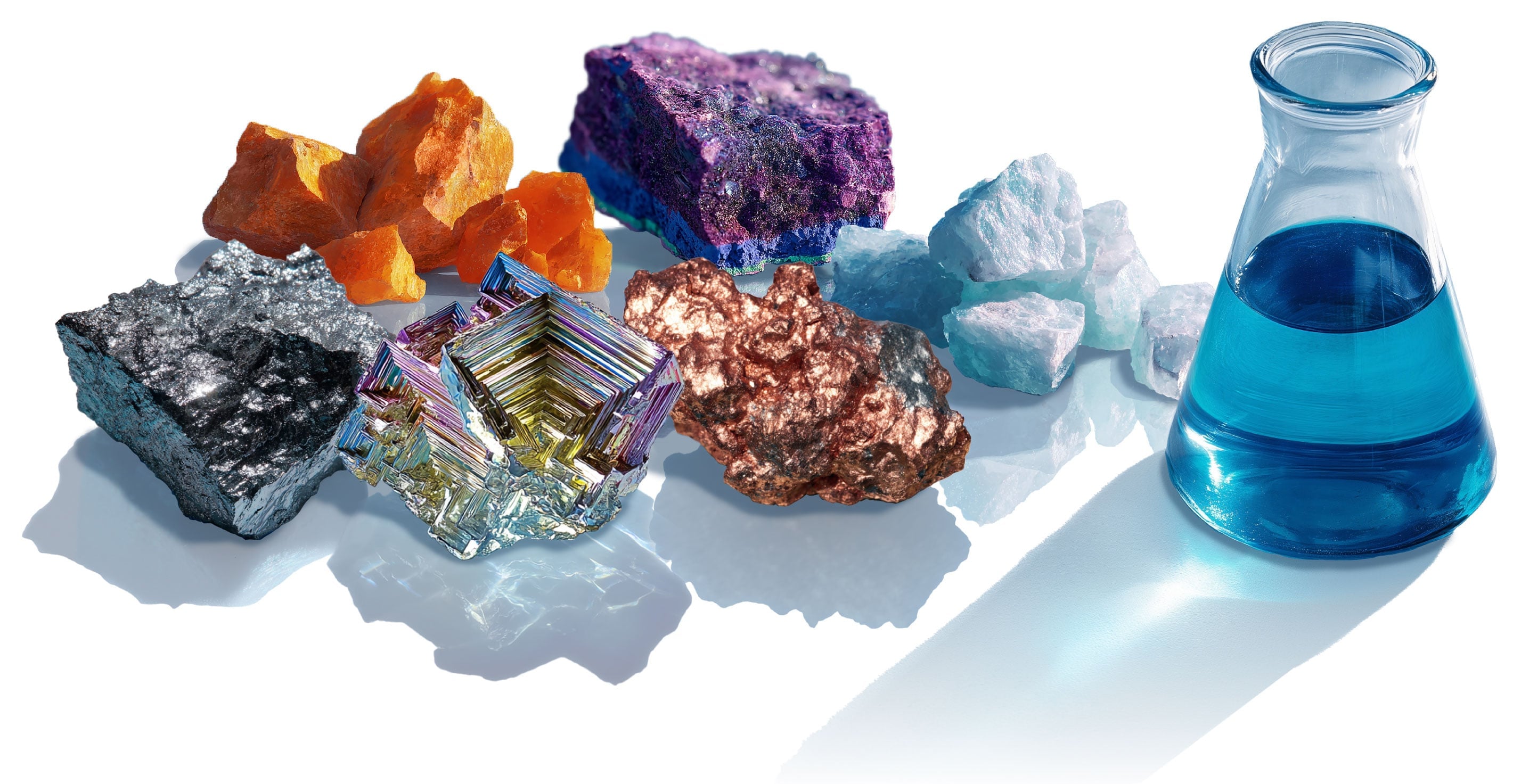 Raw mineral and metal samples beside a laboratory flask of blue solution